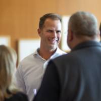 Gentleman in conversation with two others at event who are facing away from camera